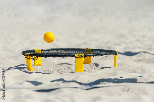 Spike ball game with yellow ball on sand. Summer game concept photo