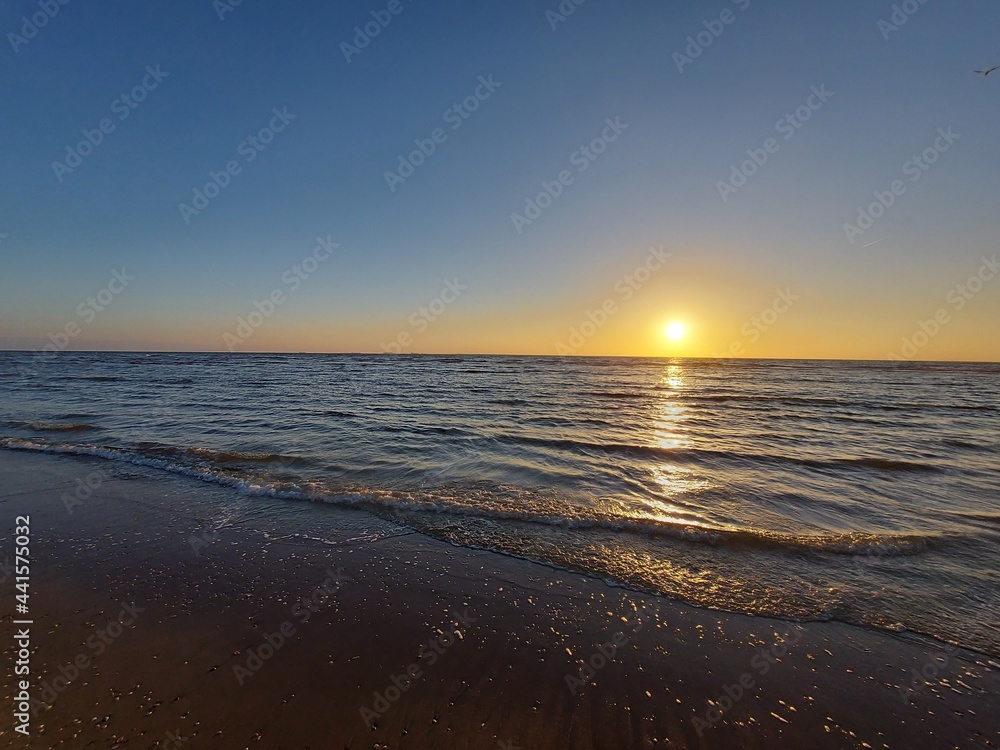 sun sinks into the sea on the beach of Katwijk with colorful sky