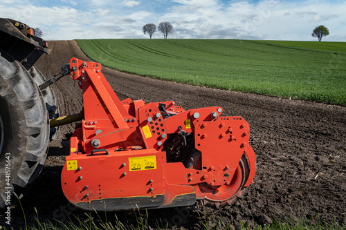 Agrarmotive - Ackerbau. Traktor und angehängter Kreiselegge auf einem Acker im Frühjahr. Acker wird für die Aussaat vorbereitet. photo