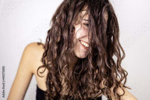 Portrait of a teen brunette girl with curly hair falling over her face