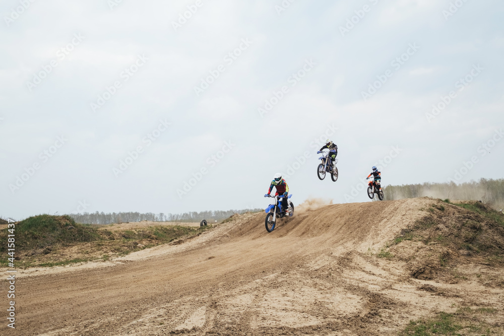 Obraz premium Motorcyclist jumping and riding on rear wheel at enduro motocross training ground