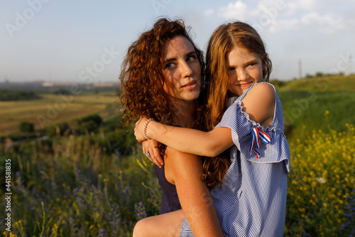 young red-haired mom and her wonderful red-haired daughter have fun outdoors dressed in dresses