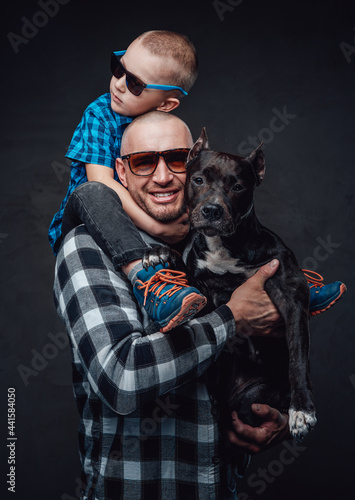 Smiling father hugging dog and his small son