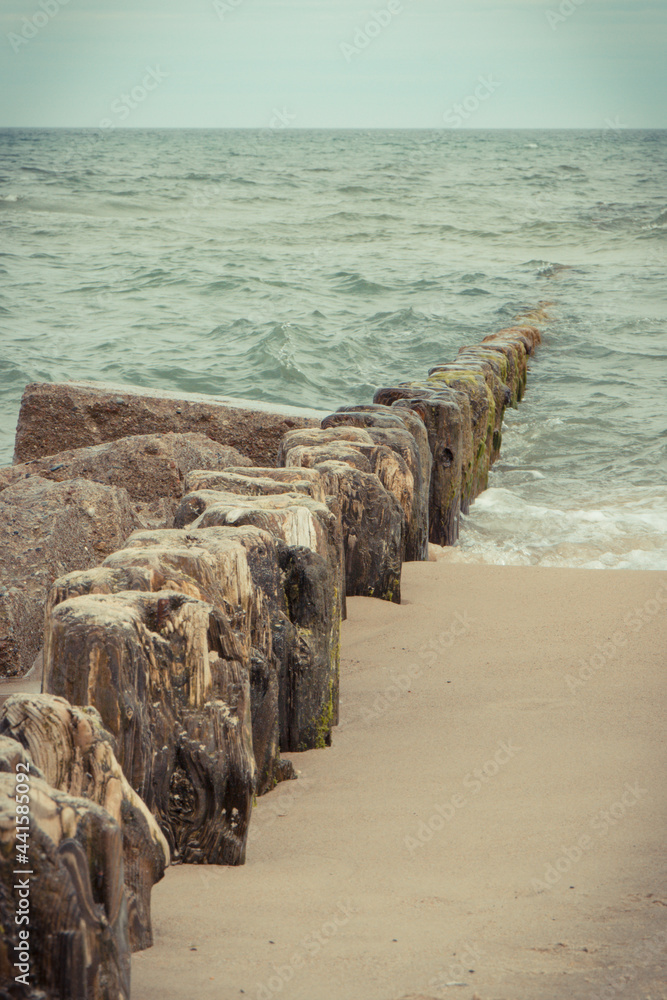 Vintage wooden breakwaters and sea waves at beach. Windy day at sea. Travel and tourism.