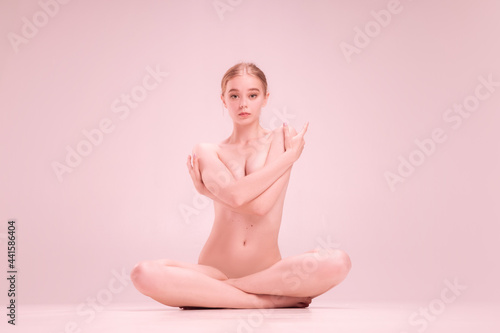 Young naked beautiful girl looking at camera isolated on pink studio background. Concept of beauty, purity, tenderness and grace. photo
