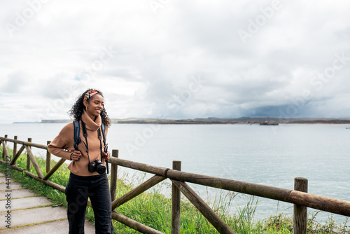 black woman photographing sea against overcast sky