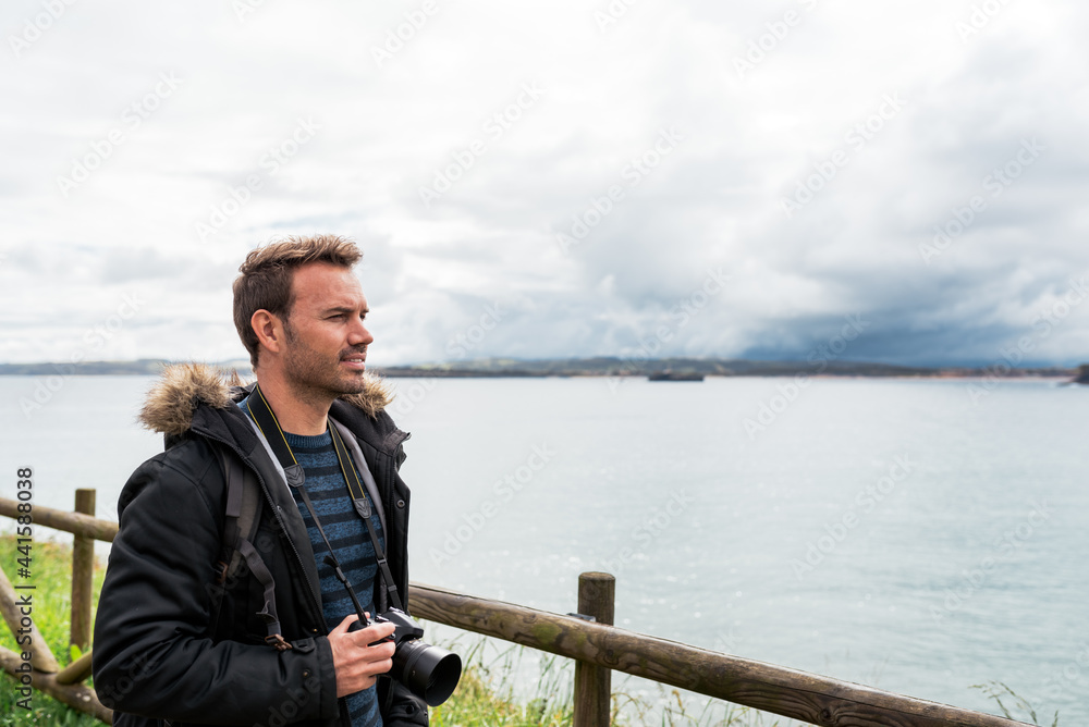 attractive Man photographing sea against overcast sky