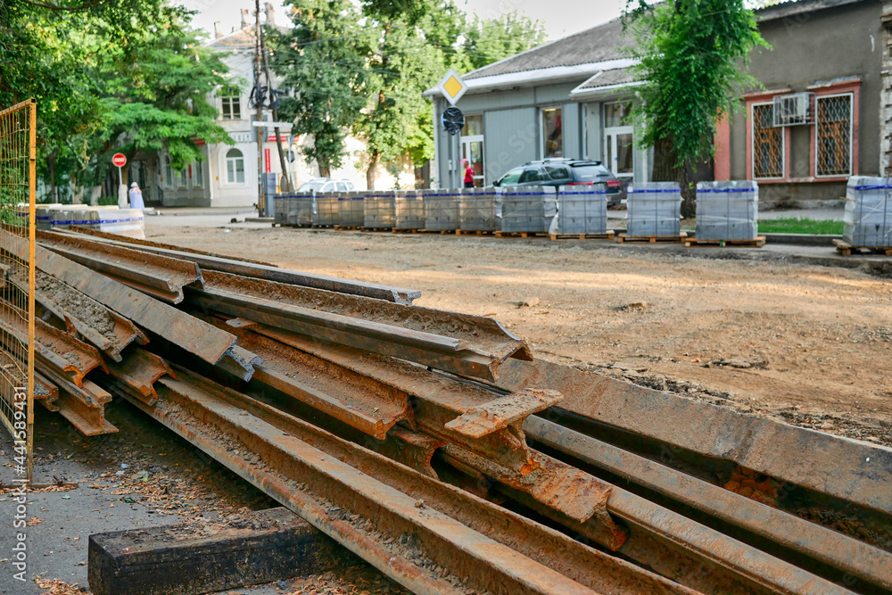 Old rusty sleepers from the streetcar tracks on the background of road works. Replacement of obsolete iron streetcar sleepers in the city during the day. Old rusty sleepers from the streetcar tracks on the background of road works. Replacement of obsolete iron streetcar sleepers in the city during the day.