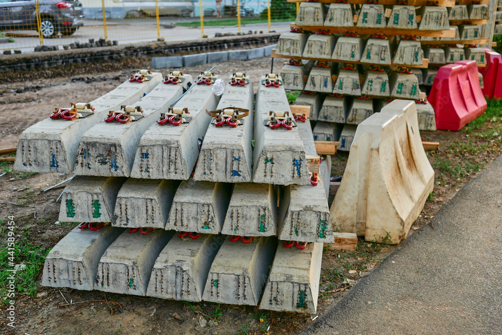A stack of concrete sleepers for streetcars against the background of road works. Concrete sleepers for streetcar tracks in the city. A stack of concrete sleepers for streetcars against the background of road works. Concrete sleepers for streetcar tracks in the city.