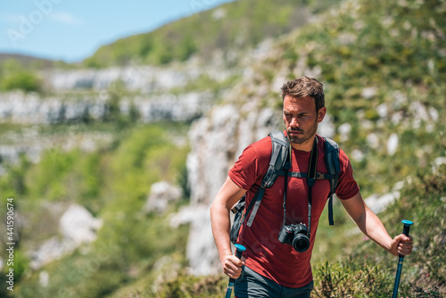 Male hiker walking with trekking poles in mountainous terrain