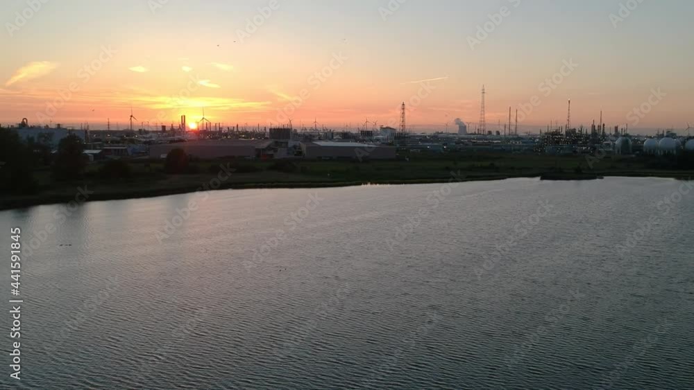 Antwerp harbor industrial buildings and golden sunset in tilting up aerial view Antwerp harbor industrial buildings and golden sunset in tilting up aerial view