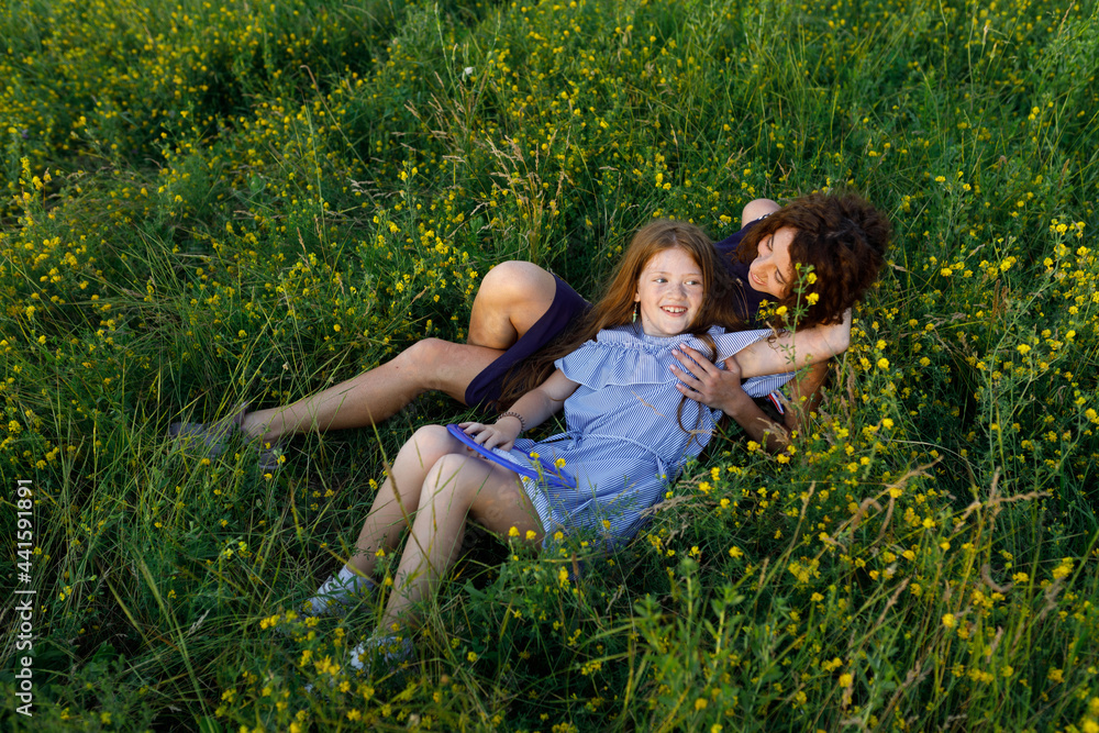 Fototapeta premium young red-haired mom and her wonderful red-haired daughter have fun outdoors dressed in dresses