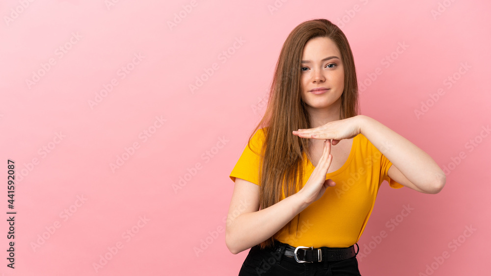 Teenager girl over isolated pink background making time out gesture Teenager girl over isolated pink background making time out gesture