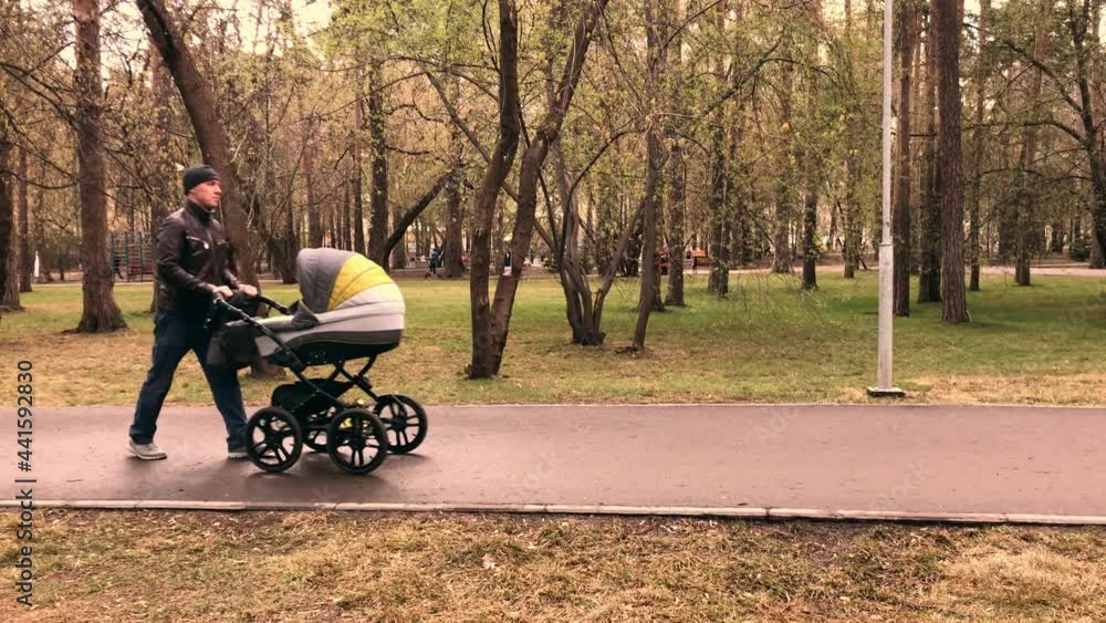Slow-motion video of father walking dawn the park with newborn baby in stroller at the evening time. High quality 4k footage Slow-motion video of father walking dawn the park with newborn baby in stroller at the evening time. High quality 4k footage