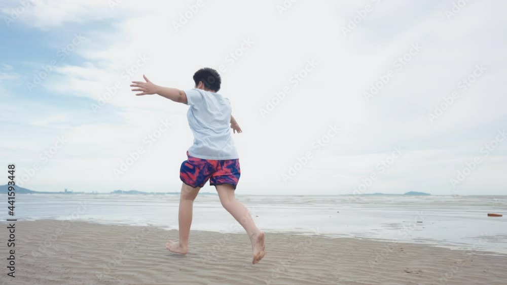 Asian cute boy running happily on the beach with cheerfulness Asian cute boy running happily on the beach with cheerfulness