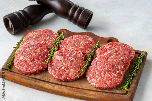 Raw beef burger patties on wooden background.