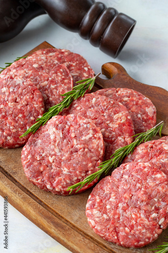 Raw beef burger patties on wooden background.