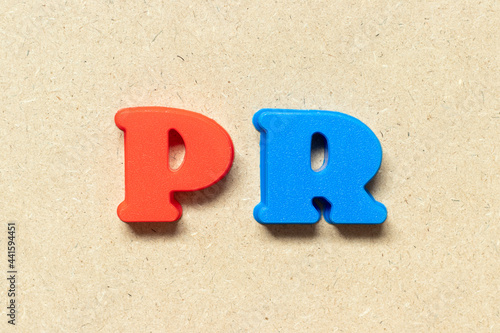 Plastic alphabet letter in word PR (Abbreviation of purchase requisition or public relations) on wood background