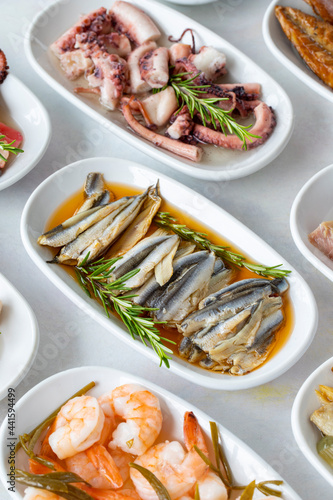 Set of Seafood Dishes. Seafood on a plate. On a white wooden background. Selective focus marinated anchovy. Lakerda, octopus salad, shrimp, fish salad photo