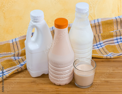 Glass of fermented milk against plastic bottles of dairy products photo