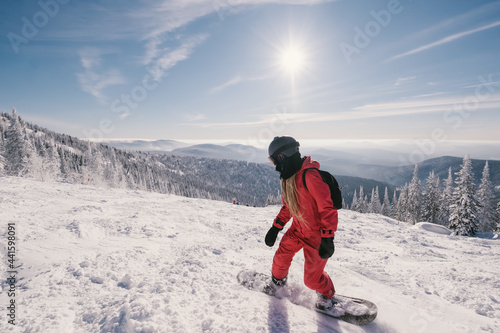 Woman riding  snowboard on  sunny snowy slope with beautiful mountain valley view. Sports outdoor lifestyle