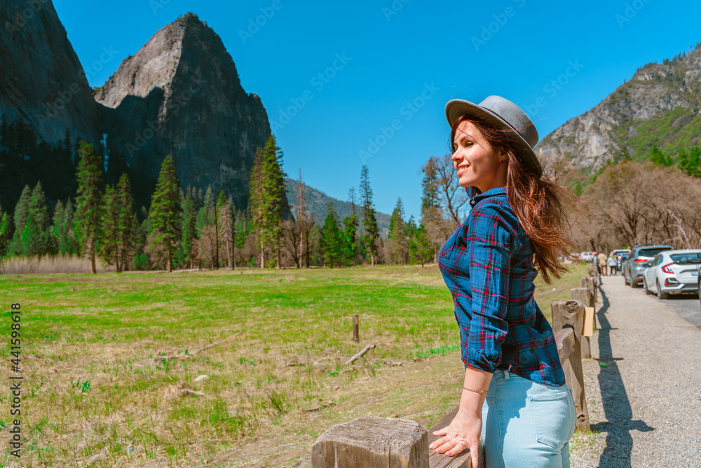 A young female tourist in a hat enjoys mountain views in Yosemite National Park