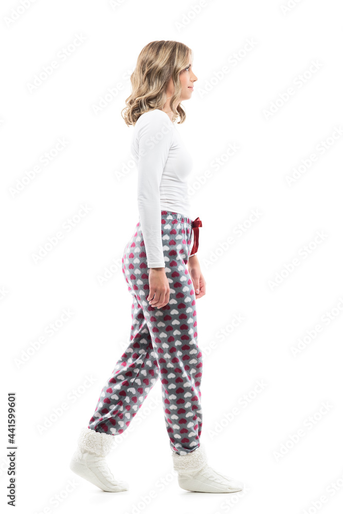 Young pretty woman in pajamas and winter socks walking and looking ahead. Side view. Full body length isolated on white background. Young pretty woman in pajamas and winter socks walking and looking ahead. Side view. Full body length isolated on white background.