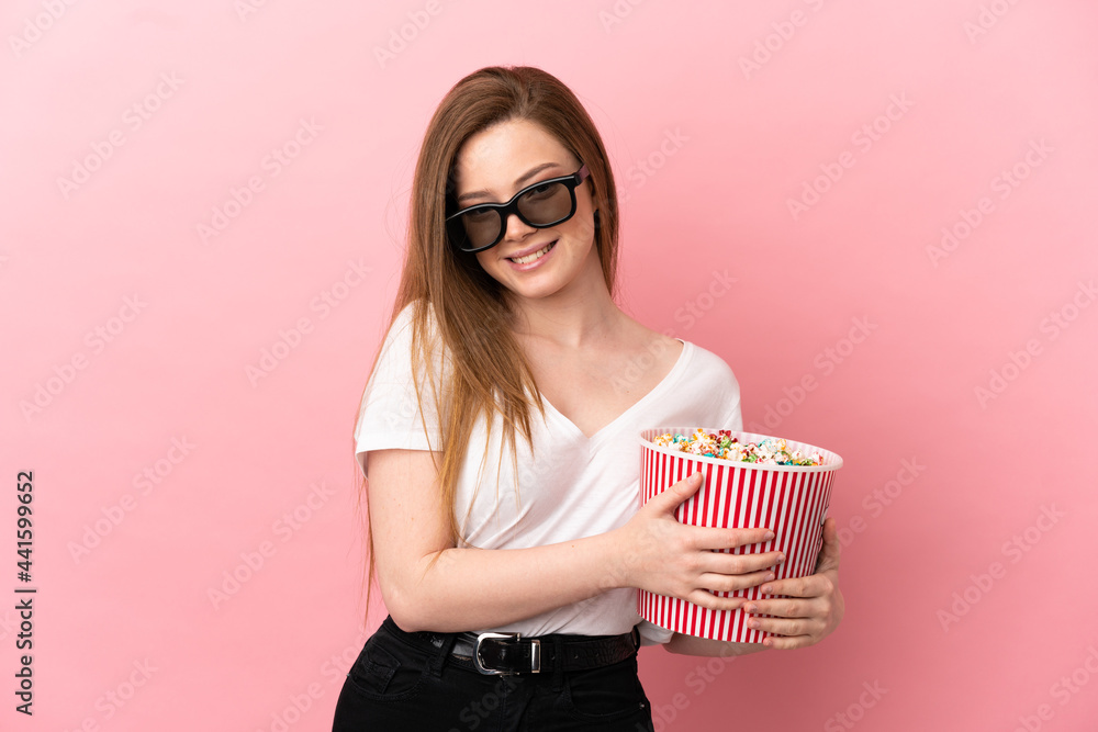Teenager girl over isolated pink background with 3d glasses and holding a big bucket of popcorns Teenager girl over isolated pink background with 3d glasses and holding a big bucket of popcorns