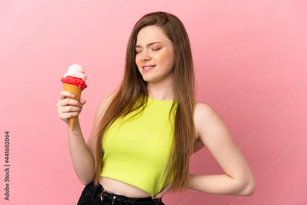 Teenager girl with a cornet ice cream over isolated pink background suffering from backache for having made an effort Teenager girl with a cornet ice cream over isolated pink background suffering from backache for having made an effort