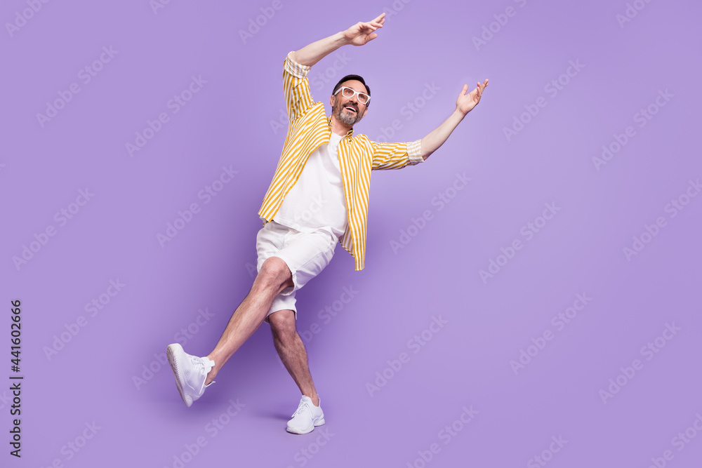 Photo of funky sweet mature man dressed striped shirt spectacles walking dancing empty space smiling isolated violet color background