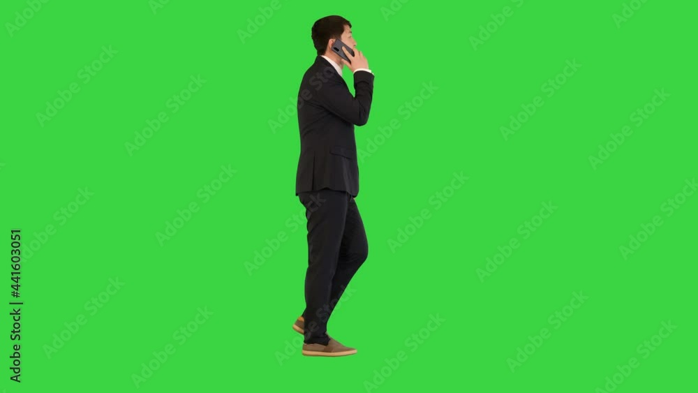 Asian businessman walks, talking on mobile phone on a Green Screen, Chroma Key. Asian businessman walks, talking on mobile phone on a Green Screen, Chroma Key.