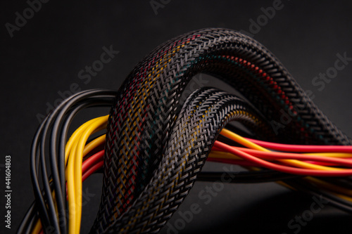 Cable snake skin. Black braided wires in bundle on black background. Braided Sleeving. Data line protection. Wire Flame-retardant nylon tube