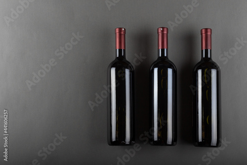 A corked three bottle of red wine on a gray office. Alcoholic drink. Winemaking concept. Space for text.
