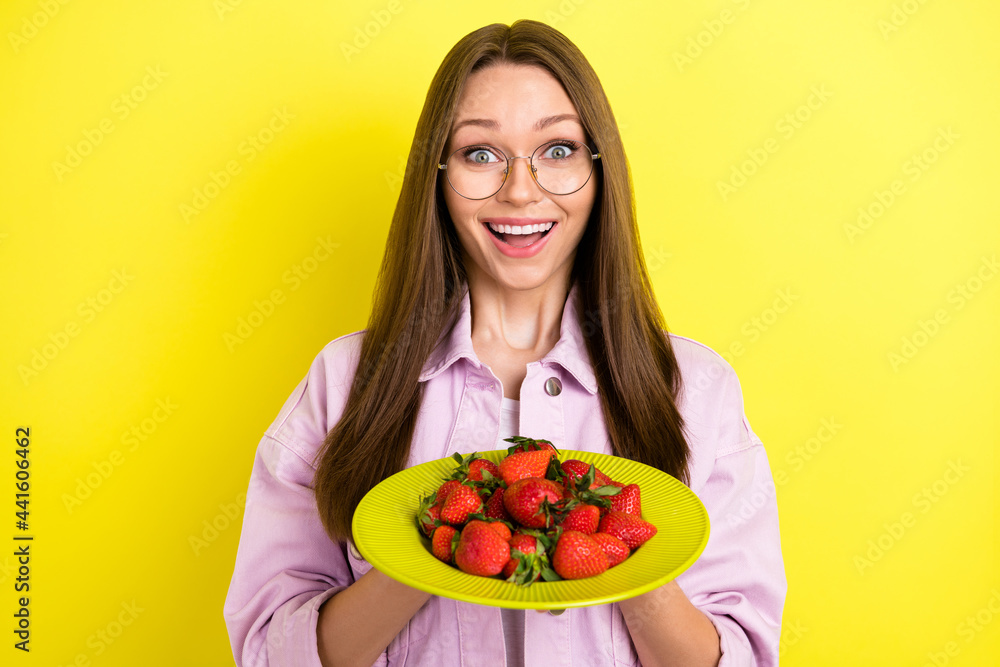 Photo of impressed brunette hairdo young lady hold fruits wear spectacles pink shirt isolated on yellow color background Photo of impressed brunette hairdo young lady hold fruits wear spectacles pink shirt isolated on yellow color background
