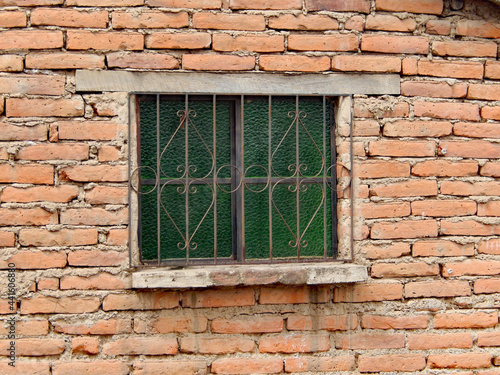 A wrought iron grate covers a window in an adobe brick house in Ecuador.