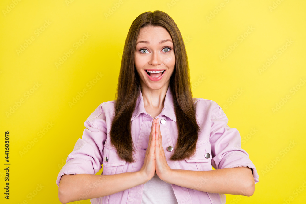 Photo portrait smiling girl keeping hands together asking wish isolated bright yellow color background Photo portrait smiling girl keeping hands together asking wish isolated bright yellow color background