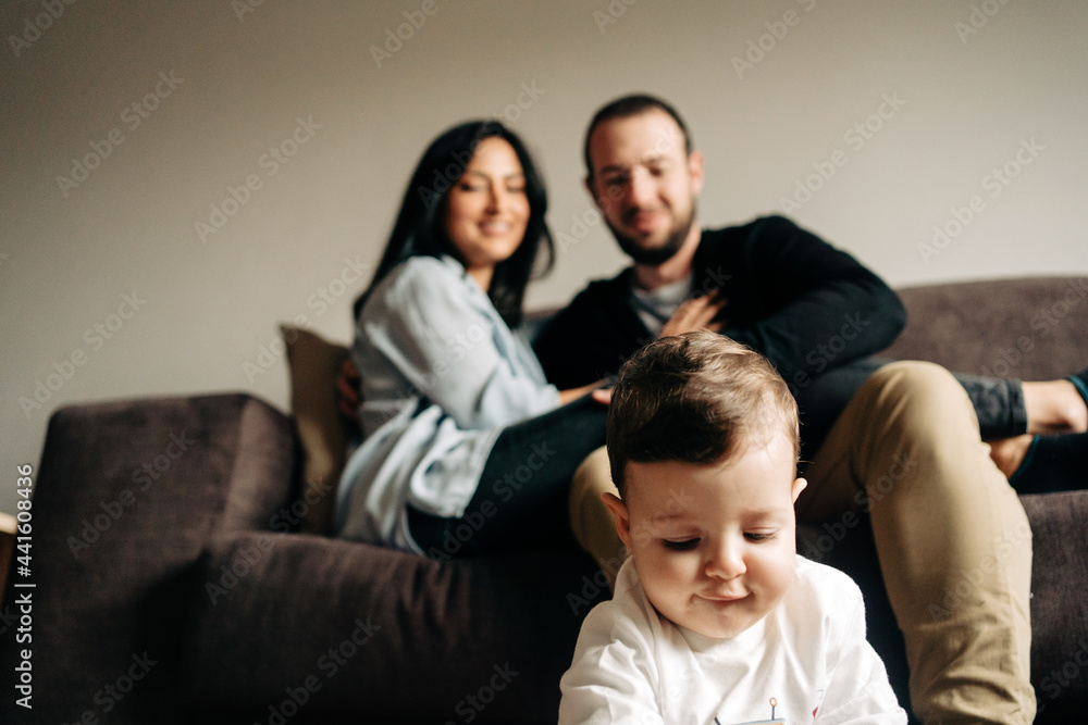 Romantic couple embracing on couch near cute little son playing on floor Romantic couple embracing on couch near cute little son playing on floor