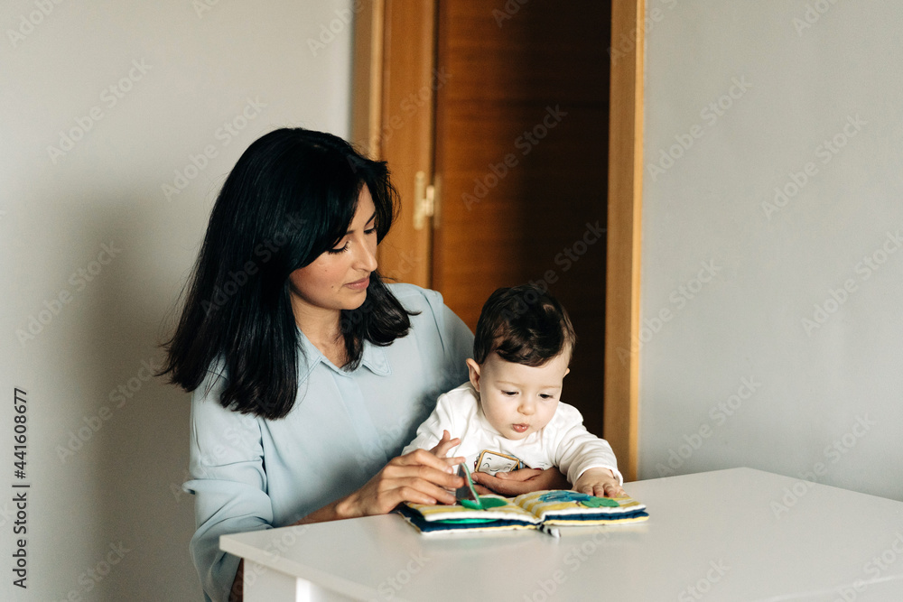 Young mother and little son reading childrens book together Young mother and little son reading childrens book together
