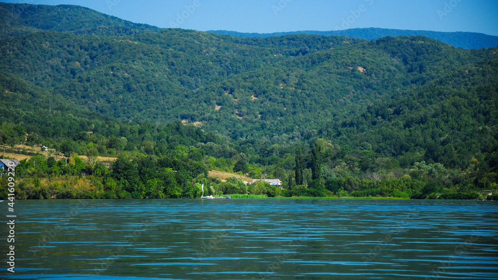 The Danube river flowing near rural villages and hills. It's blue waters flow slowly with small waves. The hilly region has plenty resorts for a nice summer vacation. Eselnita, Romania. The Danube river flowing near rural villages and hills. It's blue waters flow slowly with small waves. The hilly region has plenty resorts for a nice summer vacation. Eselnita, Romania.
