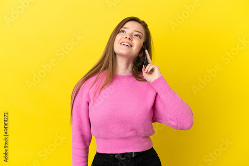 Teenager girl using mobile phone over isolated yellow background laughing © luismolinero