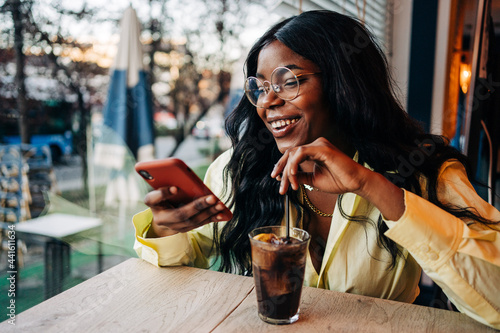 Black woman using smartphone in cafe photo