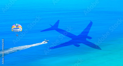 Fototapeta Naklejka Na Ścianę i Meble -  Travel concept - An passenger airplane shadow flying towards a tropical Oludeniz beach - Happy people parasailing on Oludeniz Beach in summer - Fethiye, Turkey