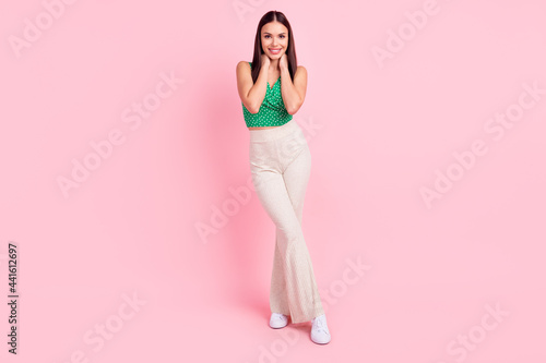 Full size photo of good brown hairdo young lady stand wear green dotted top trousers isolated on pink color background