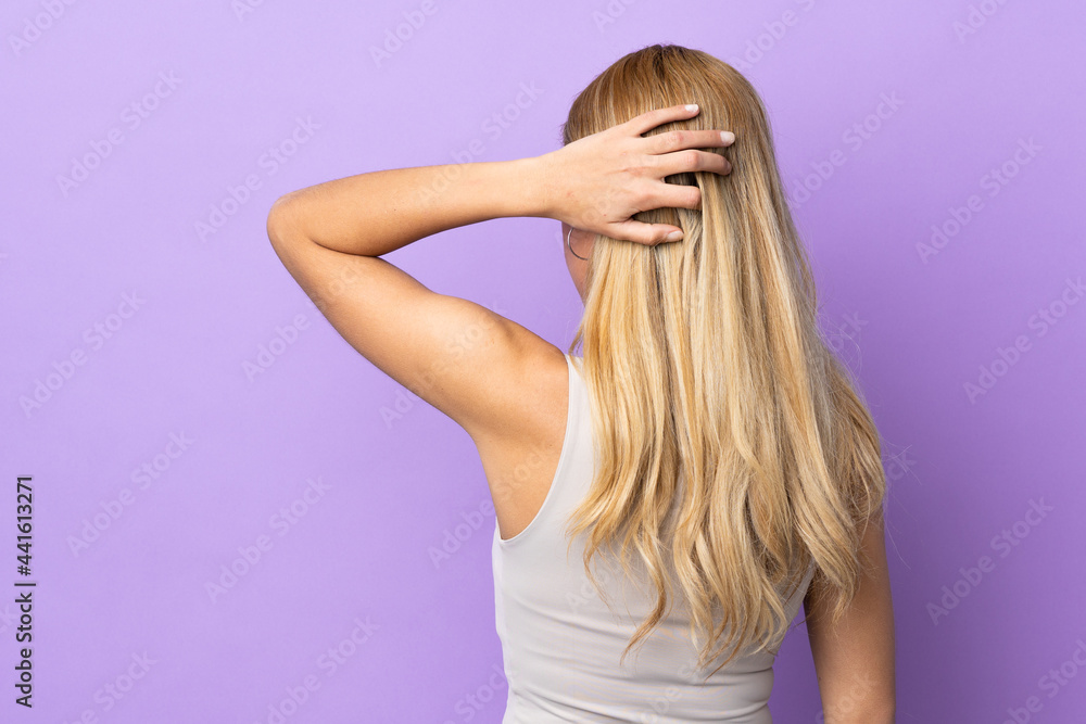 Young Uruguayan blonde woman over isolated background in back position and thinking Young Uruguayan blonde woman over isolated background in back position and thinking