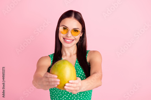 Photo portrait woman smiling in green top keeping mango isolated pastel pink color background