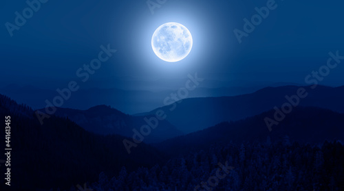 Beautiful landscape with blue misty silhouettes of mountains against super blue moon 