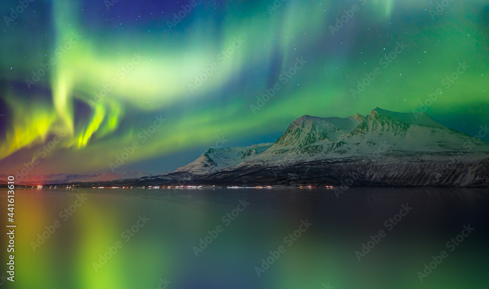 Northern lights or Aurora borealis in the sky over Tromso, Norway - Aurora reflection on the sea on the background Norwegian fjord and mountains - Winter season.