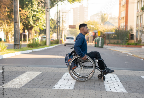 Foto profile of black man with wheelchair crossing the street.