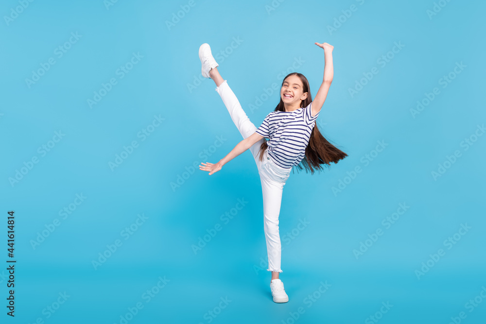 Full length photo of young excited preteen girl happy positive smile gymnastics isolated over blue color background Full length photo of young excited preteen girl happy positive smile gymnastics isolated over blue color background
