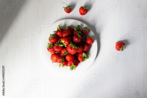 strawberries in a bowl on white wooden background